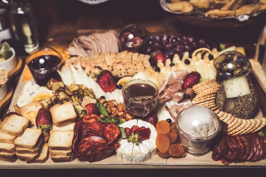 Plateau gourmand avec fromages, charcuterie, fruits, noix, confiture et biscuits, idéal pour un apéritif convivial.
