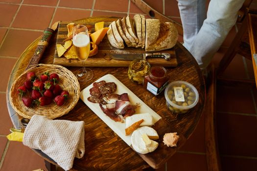 Table en bois avec charcuterie, fromages, pain, fraises et boissons, idéale pour un apéritif gourmand à partager.